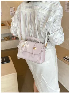 Detail view of lavender square handbag with metal twist lock and pearl lace charm