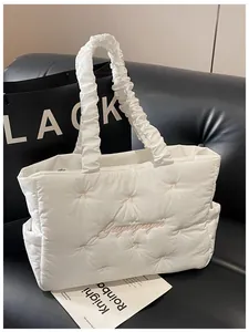 Detail of white quilted nylon tote with pink embroidery and ruffled scrunchie shoulder strap