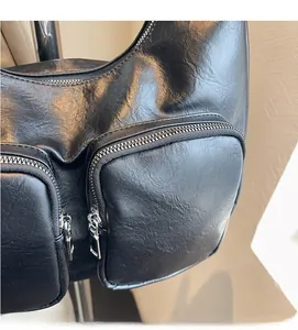Detail of black textured PU leather underarm bag with dual silver zip pockets