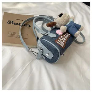 Detailed view of light blue denim Boston bag with puppy pendant and adjustable strap
