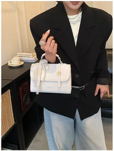 Detailed view of cream PU leather handbag with gold clasp and pearl lace charm accessory