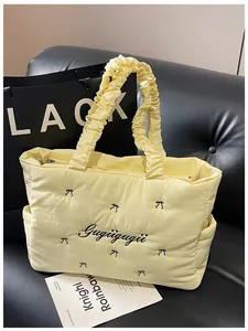 Close-up of yellow quilted tote bag featuring a black bow and ruffled frill handles