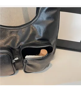 Detail of black pleated faux leather shoulder bag with dual silver zip exterior pockets
