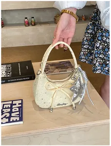 Detailopname van de beige handtas met strik, sterrenprint en zilveren sterhanger
