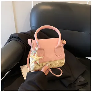 Detail of pink leather and straw mini bag featuring a starfish charm and top handle