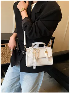 Detail of cream white PU handbag featuring delicate lace bow and pearl chain handle