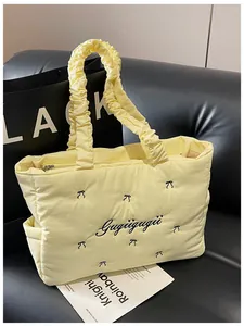 Detail of light yellow quilted tote bag with embroidered bow and ruffled handle