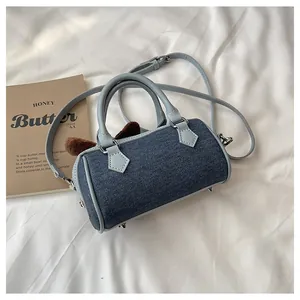 Detail of denim Boston bag with plush ears, leather handles and protective metal feet
