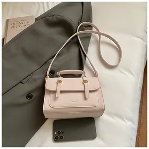 Detail of light beige crossbody bag with gold hardware and smartphone for size reference