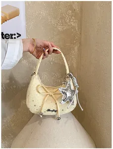 Detail van crème halve maan tas met zilveren sterren en decoratieve metalen strik
