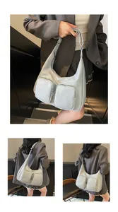 Detail of light blue hobo bag showing glossy texture and two square front zipper pockets