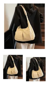 Detail of a creamy white oversized hobo bag featuring dual front zipper pockets and texture