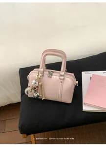 Detail of light pink Boston handbag with glossy leather finish and decorative charms