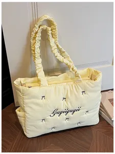 Detail of quilted nylon tote with black bow embroidery and ruffled scrunchie handle