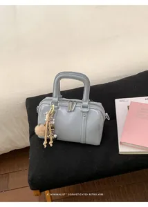 Close-up of light blue mini Boston bag with plush charm and BEAR BAGS logo detail