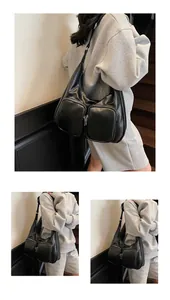 Detail view of black faux leather underarm bag featuring dual front zipper pockets