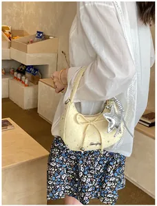 Detail van beige crossbodytas met zilveren sterren, strik en stervormige hanger