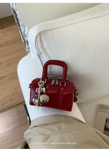Detail of red cylinder handbag with luxury metal zipper and elegant charm on sofa