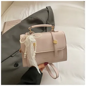 Detail of pink faux leather handbag featuring elegant pearl and white lace bow charms