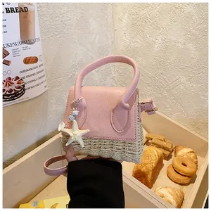 Close-up of pink leather and woven straw mini bag with starfish charm on wooden tray