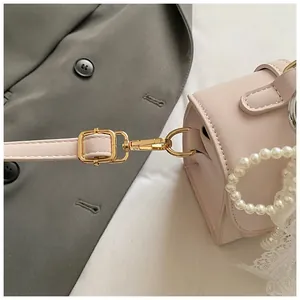 Detail of pink PU leather bag with golden hooks, pearl beads and lace pendant