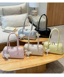 Sacs Boston colorés avec breloques perles et nœuds en dentelle sur table en bois