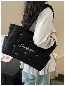 Quilted black nylon tote bag with bow embroidery and ruffled shoulder strap detail