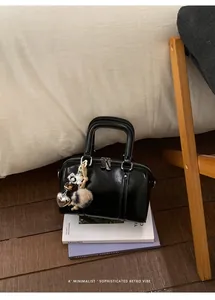 Close-up of black glossy pillow bag with silver heart charms on decorative book props
