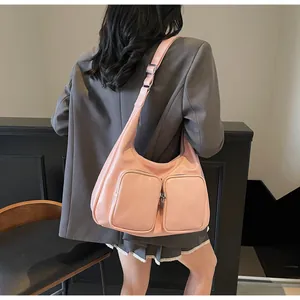 Detail view of a pink hobo bag with double front zip pockets and wide adjustable strap