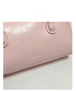 Détail du sac sous l'aisselle en cuir imprimé rose avec logo mode embossé élégant