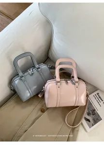 Detail of glossy pastel pillow bags with silver zippers and removable leather straps