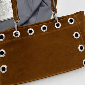 Detail showing the dark brown suede fabric and silver metal eyelets of the baguette bag