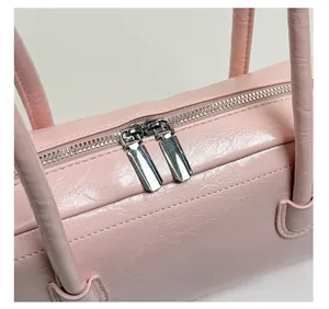 Détail du sac en cuir rose avec doubles fermetures éclair argentées et texture grainée