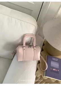 Detailed view of pink leather mini Boston bag with ZEM & BAGS logo on a white sofa
