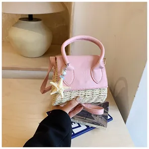 Close-up of a mini straw handbag with pink leather top and a white starfish charm
