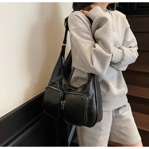 Detail of black crescent hobo bag with dual functional front zipper pockets and wide strap