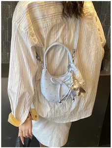 Detail van lichtblauwe hobo-tas met gouden sterren, strik en ster-hanger
