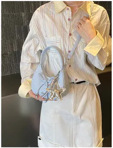 Detail van de lichtblauwe suède crossbodytas met sterpatronen en een zilveren sterhanger