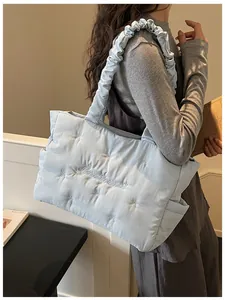 Detail of light blue quilted nylon tote featuring bow embroidery and scrunchie shoulder strap