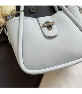 Detail of light blue lychee texture leather bucket bag with silver turn-lock and plush charm