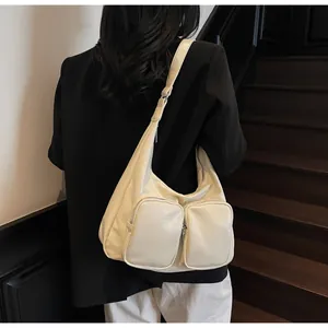 Close-up of cream underarm bag with double front zip pockets and silver hardware detail