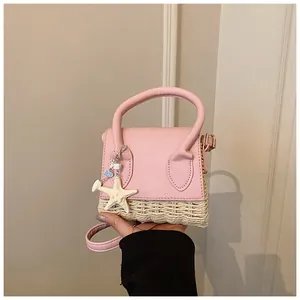 Detail of pink leather and straw mini bag featuring a decorative white starfish charm