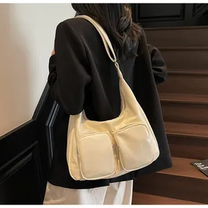 Detail of off-white Hobo bag with dual zipper pockets and textured leather on a model