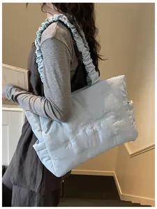 Macro detail of light blue quilted nylon tote with bow embroidery and ruffled handles