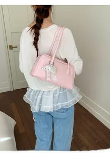 Détail d'un sac rose avec nœud en dentelle et pendentif cœur en perles sur modèle