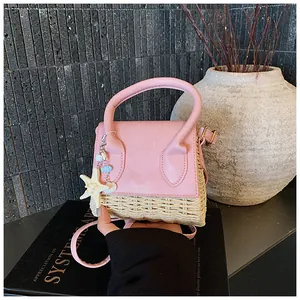 Detail of pink leather and straw mini bag with starfish and seashell charms on a strap