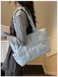 Detail of light blue quilted nylon tote with bow embroidery and ruffled shoulder straps