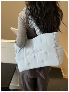 Light blue quilted nylon tote bag featuring bow embroidery and ruffled shoulder straps