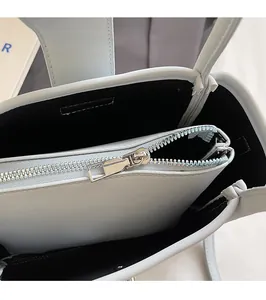 Detail view of smooth silver zipper and interior lining of light blue litchi pattern bucket bag