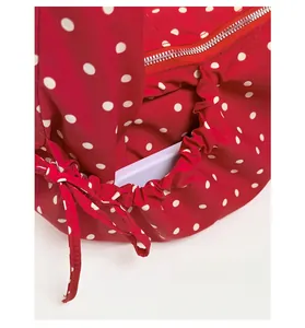 Close-up of red polka dot underarm bag featuring a drawstring side pocket for storage